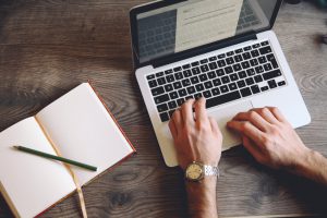 open notebook on a wooden table, a wristwatch and a pen, analog camera, a laptop. writer's setup, seeking inspiration or just a quick note.