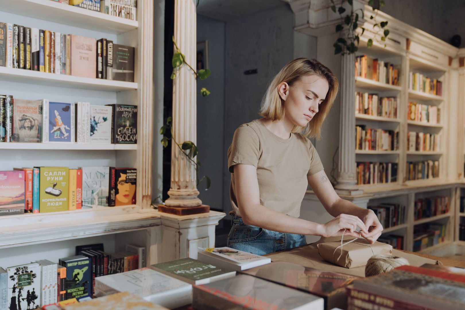 Eine Frau in einer Buchhandlung packt ein Buch als Paket ein.