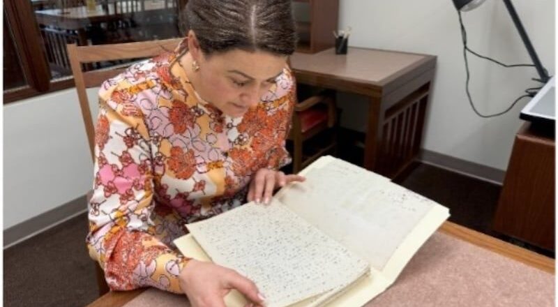 Frau liest ein aufgeschlagenes Manuskript an einem Schreibtisch